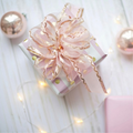 Pink and white holiday gift boxes with a large pink ribbon and warm string lights